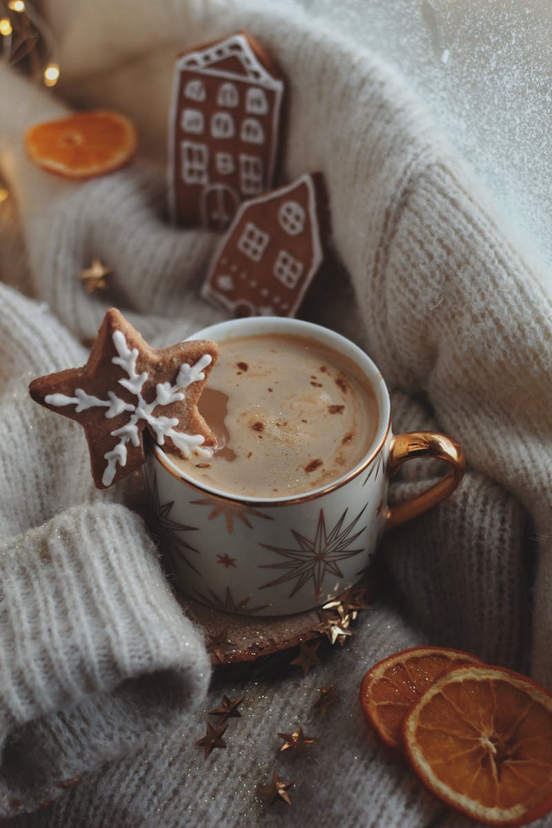 A cozy winter scene with a star mug, gingerbread cookies, and dried oranges.
